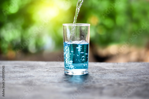 Pour water onto a glass of water with splash on nature background