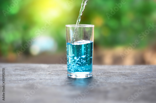 Pour water onto a glass of water with splash on nature background