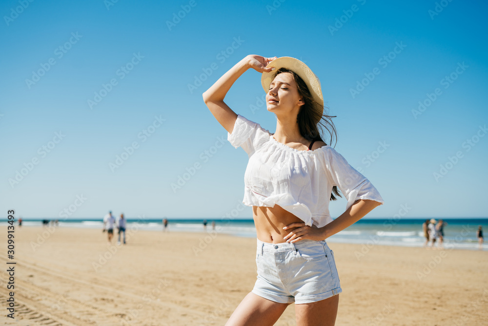 girl stands on the beach in profile, gracefully grotesquely arching her back and holding her hat to her hand, the second hand to the side girl stands on the beach in profile, gracefully grotesquely arching her back and holding her hat to her hand, the second hand to the side