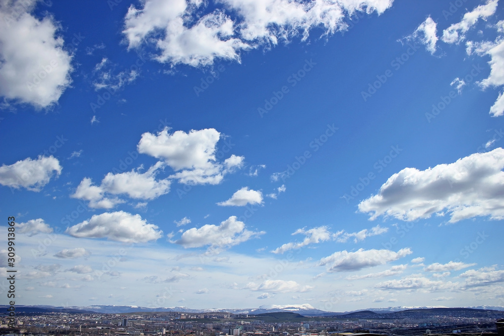 White clouds about the city in blue sky. Place for design. Natural concept.