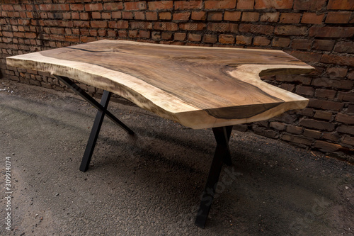 Wooden stylish table made of solid walnut with epoxy resin on the background of a brick wall