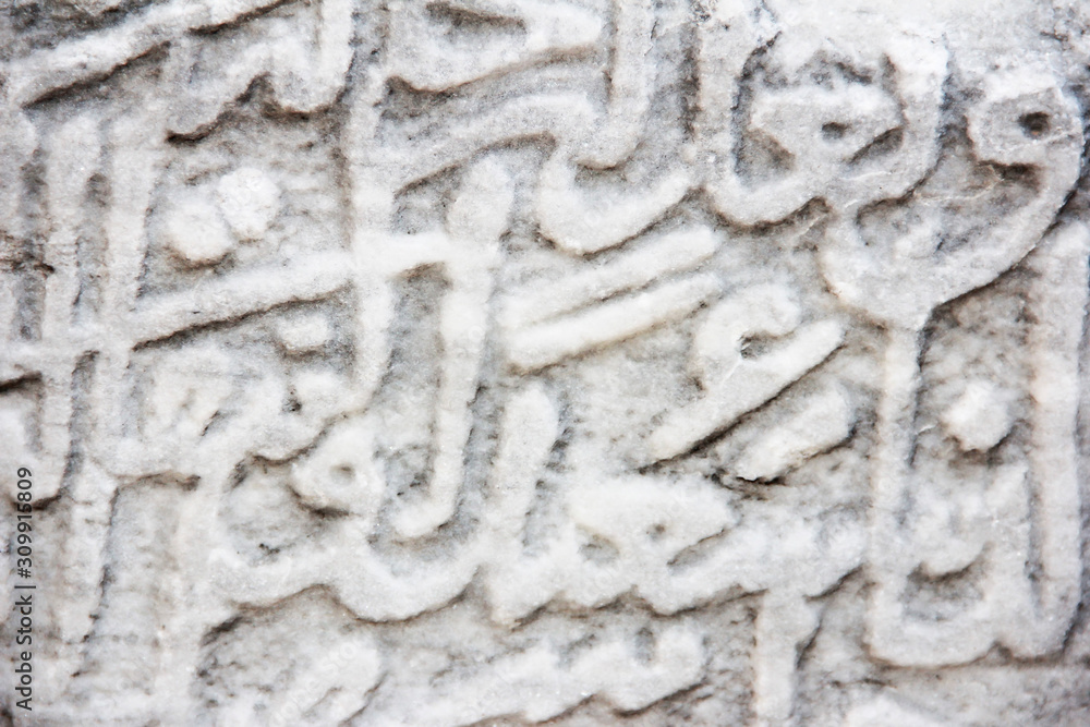 fragment of a gray stone wall depicting oriental patterns hieroglyphs