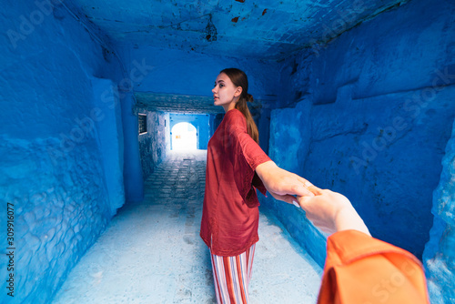 street corridor in the blue city of Morocco, the girl wants to go into the distance, her hand holds © nelen.ru
