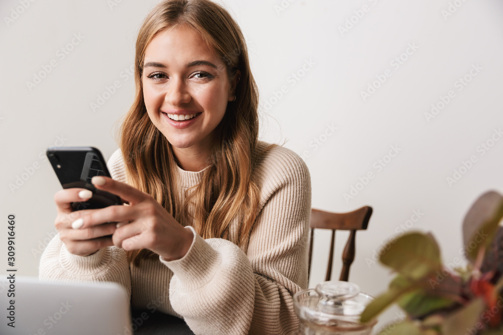 Image of smiling caucasian woman using laptop and smartphone Image of smiling caucasian woman using laptop and smartphone
