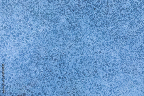 The macro or closeup shot of ice texture or background with stars on the puddle or pool in the frost winter weather