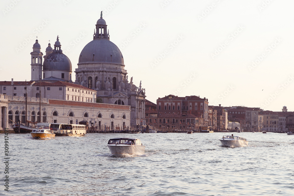 Classical view of Venice from a boat. Evening light, ancient building, wide river with boats with tourists. Nice touristic adventure