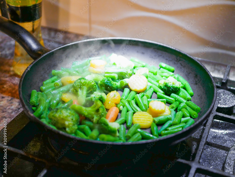 Vegetables fried in a pan close-up. Steam is coming. Defocus. vegetarian barely. Eco food. Vegetables fried in a pan close-up. Steam is coming. Defocus. vegetarian barely. Eco food.