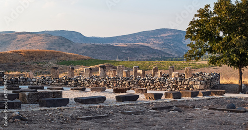 ruins of an israelite stone storehouse made with pillars and columns at the tel hazor archaeological park in israel with the canaanite city and kibbutz ayelet shahar in the background photo