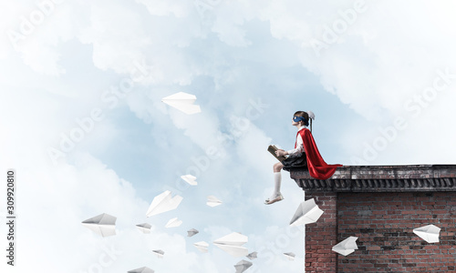 Girl power concept with cute kid guardian against cloudscape background. Mixed media