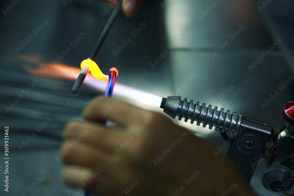 The process of blowing glass bead products. Hand made glass beads in the fire out of red hot glowing glass for bracelets.
