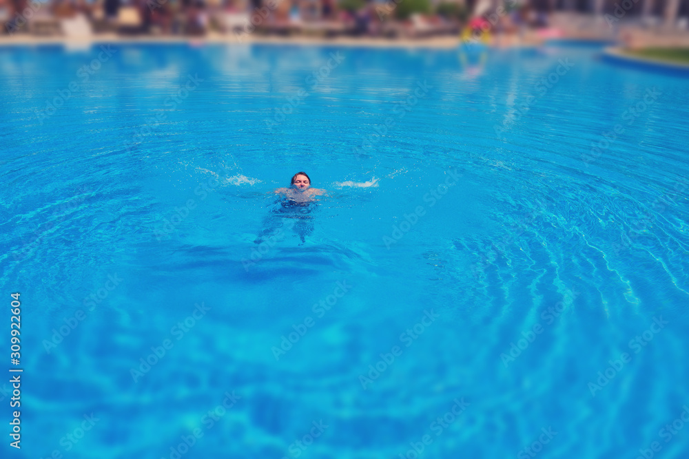 Naklejka Woman drowns in pool water, tilt shift blurred effect