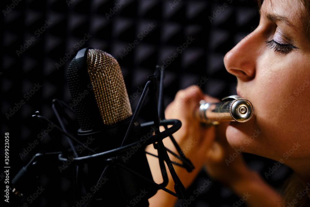 Girl flute in headphones player plays in recording studio, closeup