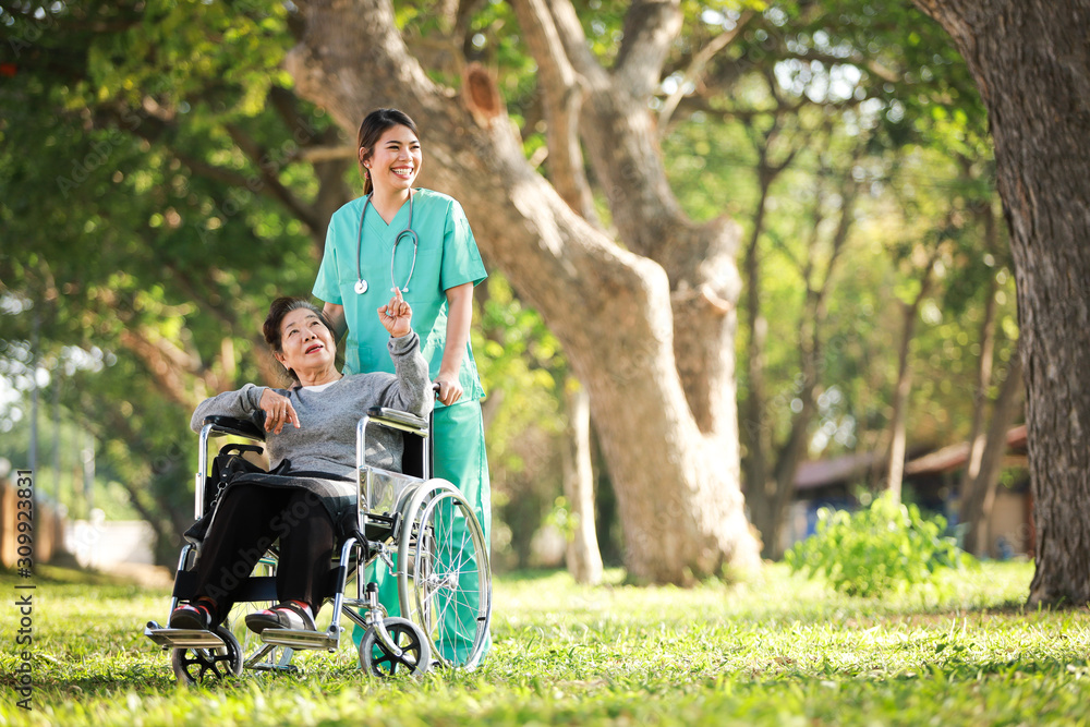 Asian senior woman sitting on the wheelchair with woman in doctor uniform in the park hospital Asian senior woman sitting on the wheelchair with woman in doctor uniform in the park hospital