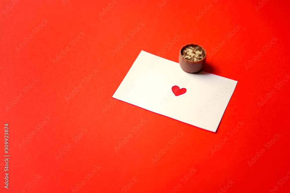 St. Valentine's Day. Chocolate candies and a note with a heart on red background. Chocolate candies. Chocolate treats. Assorted chocolates. St. Valentine's Day. Chocolate candies and a note with a heart on red background. Chocolate candies. Chocolate treats. Assorted chocolates.