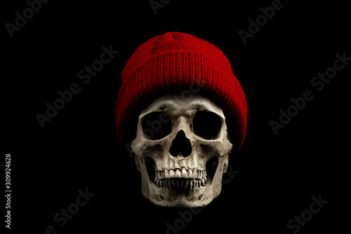 Human skull with red knitted wool beanie hat isolated on black background. Winter concept.