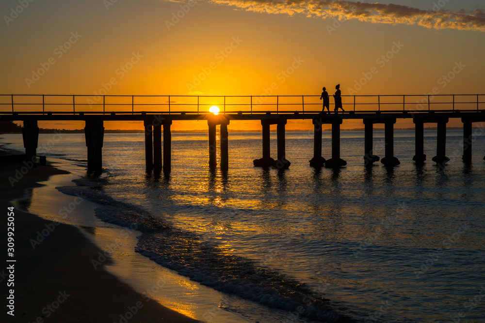 Obraz premium Seaside jetty silhouetted at sunset.
