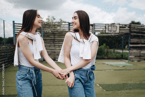 Bilde på lerret Portrait of Two Young Brunette Twins Sisters Dressed Alike in Jeans and White T-