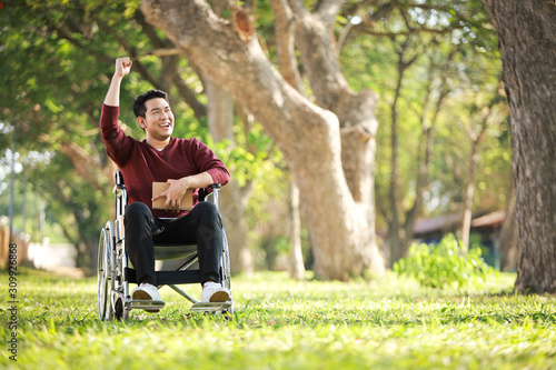 Asian Young Man sitting on the wheelchair in the park hospital