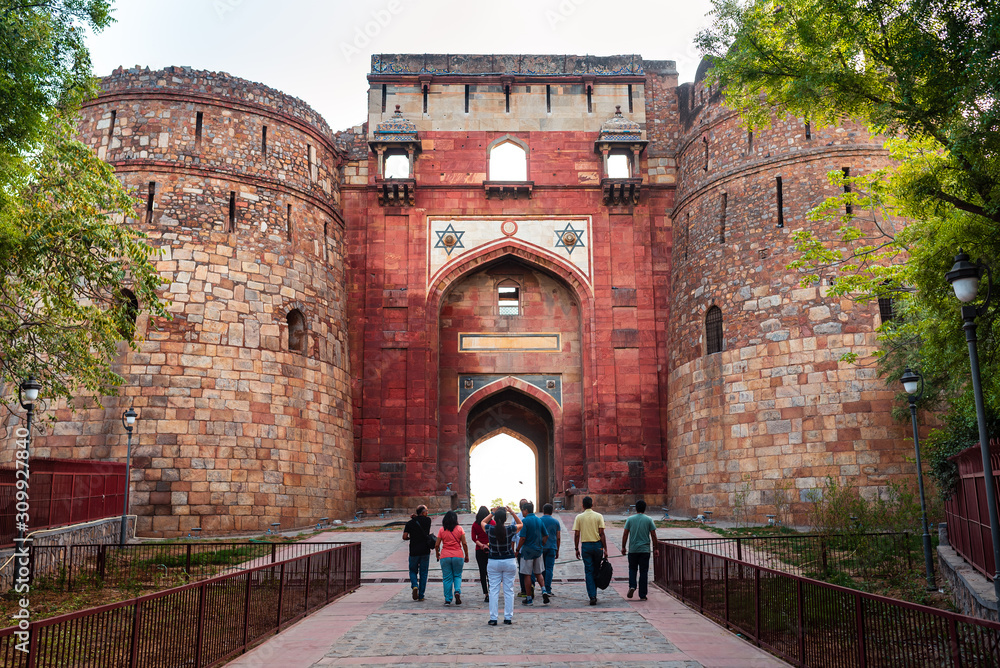 Tourists entering the large entrance gate of a famous monument in Delhi, India. Also known as Purana Qila or Quila.