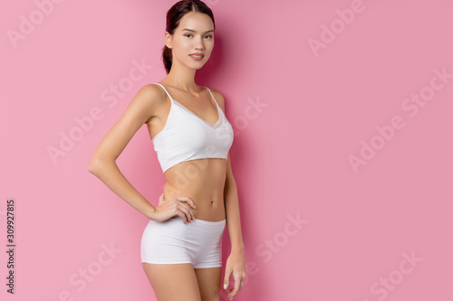 portrait of beautiful attractive nice charming lady with slim athletic body stand isolated over pink background, look at camera, wearing white underwear