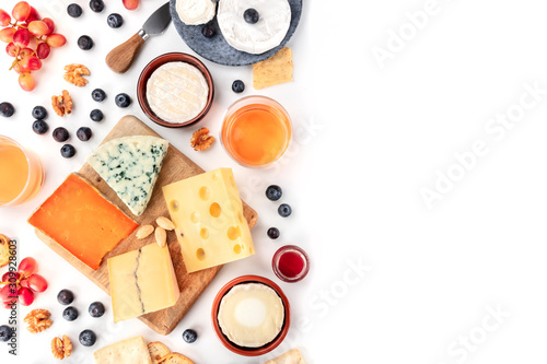 Cheese board background, a flatlay top shot on white with copy space. Blue cheese, red Leicester, Emmental, goat cheese, Brie and others with wine, fruits, nuts and almonds, with a place for text