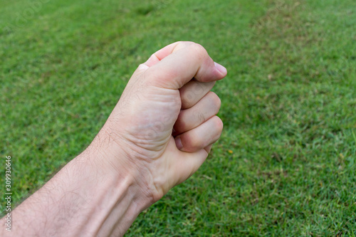 Conceptual angry fist and hand on green grass. Powerful, strong, stress, agressive concepts. © KingmaPhotos