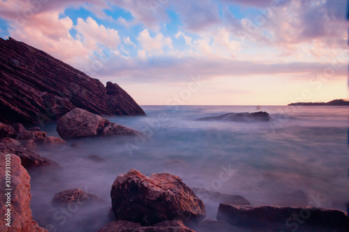 Pink is the blue sea.Sunset sea romantic landscape with bright saturated colors, rock stones.