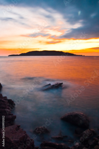 Pink sunset with clouds. Sunset sea romantic landscape with bright saturated colors  rock stones.
