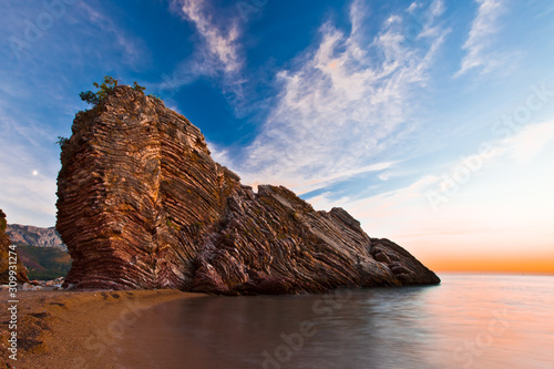 Cliff by the sea at sunset. Sunset sea romantic landscape with bright saturated colors, rock stones.