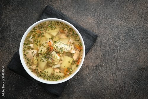 Fresh homemade fish soup with vegetables in bowl on black background, top view with copy space. photo