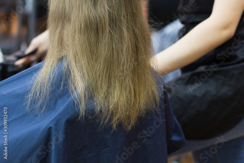 Hair of child before cutting sitting in special chair in hairdresser