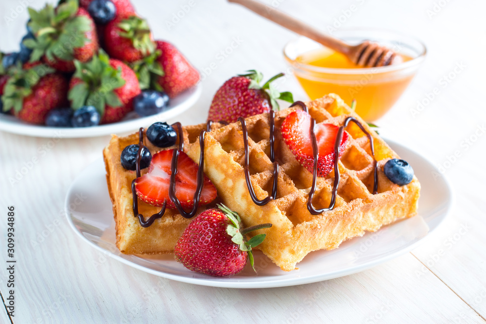 Fresh homemade food of berry Belgian waffles with honey, chocolate, strawberry, blueberry, maple syrup and cream. Healthy dessert breakfast concept with juice Fresh homemade food of berry Belgian waffles with honey, chocolate, strawberry, blueberry, maple syrup and cream. Healthy dessert breakfast concept with juice