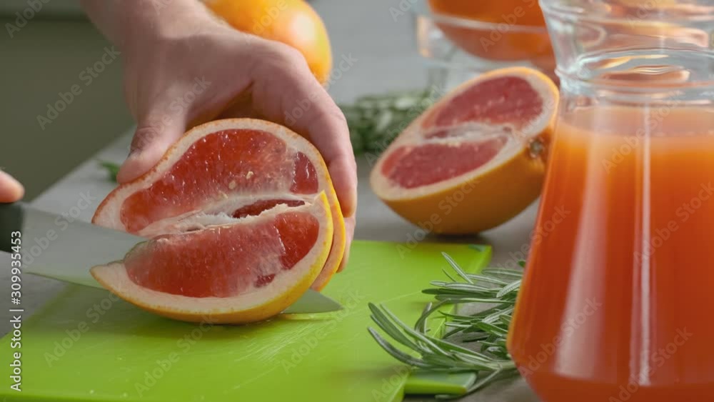 Male hand cuts fresh grapefruit on a cutting board. Concept of the ingredients for lemonade or cocktails. Sweet grapefruit. Citrus fruit Male hand cuts fresh grapefruit on a cutting board. Concept of the ingredients for lemonade or cocktails. Sweet grapefruit. Citrus fruit