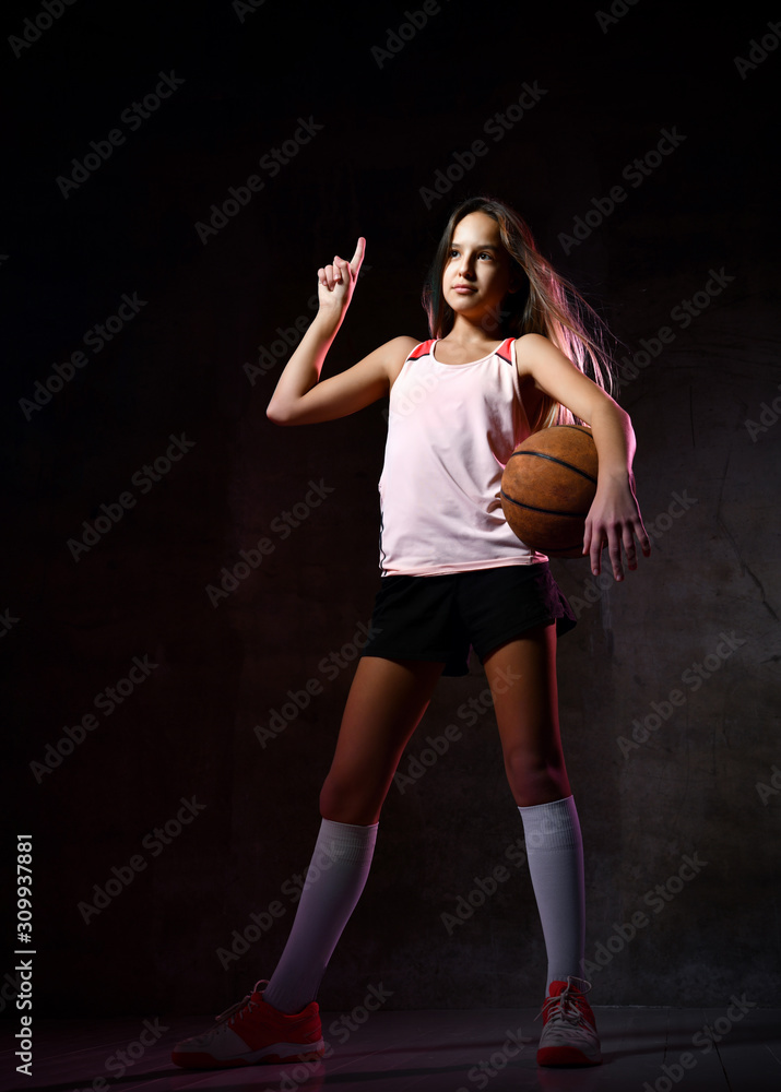 Beautiful caucasian teen woman in sportswear playing basketball . Sport concept isolated on black background. Beautiful caucasian teen woman in sportswear playing basketball . Sport concept isolated on black background.