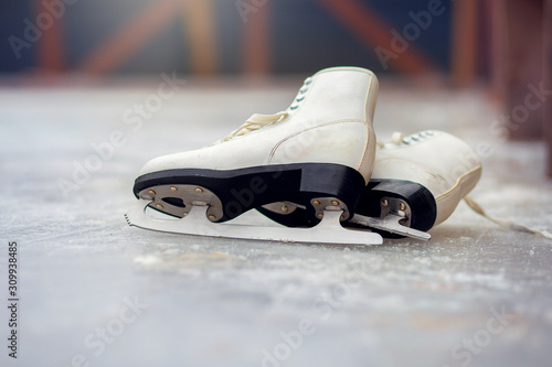 White ice skates for figure skating lie on an ice rink
