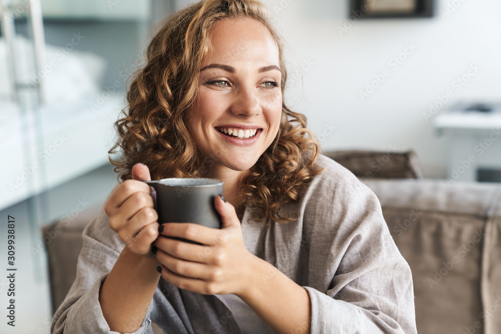Cheerful young blonde haired woman drinking tea - obrazy, fototapety, plakaty 