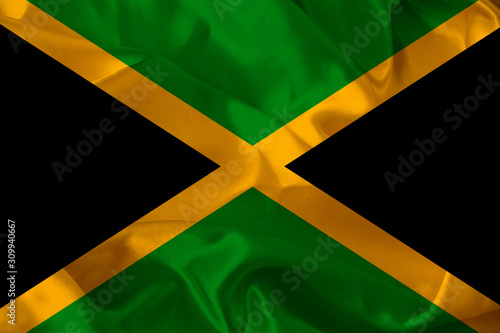 colored national flag of the modern state of Jamaica on beautiful pleated silk fabric, concept of tourism, economic and political development, global business