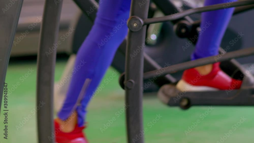 Woman in red shoes using exercise machine Woman in red shoes using exercise machine