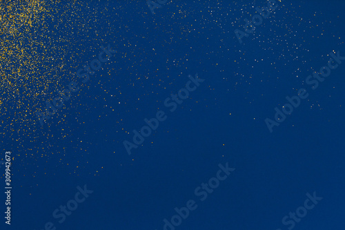 Gold glitter texture on a blue background. Design element. Golden explosion of confetti.