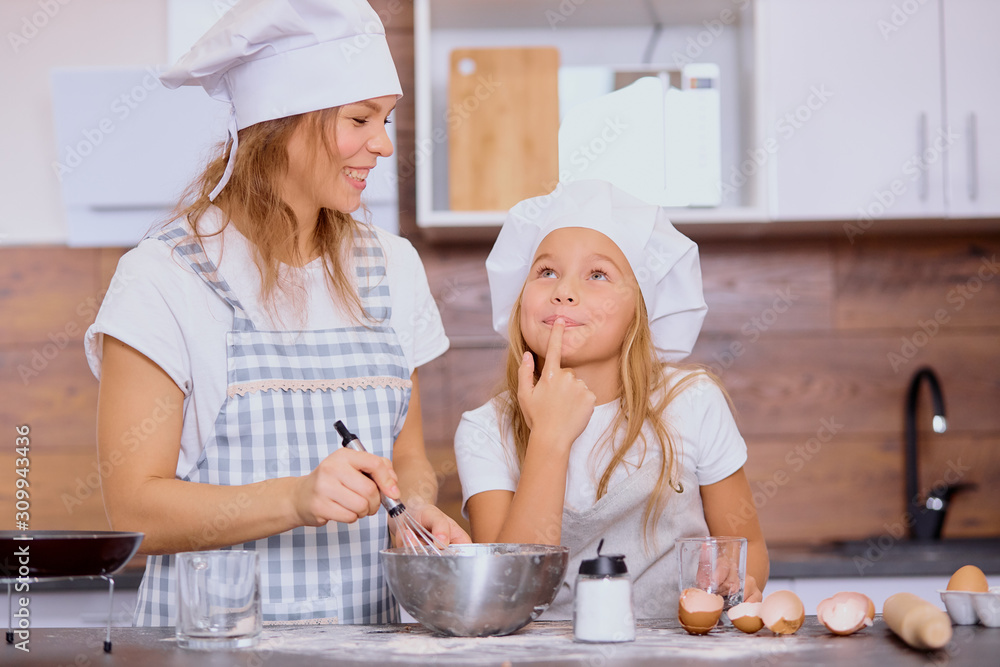 caucasian mother and daughter bake together, make dough and use ingredients need for it. Happy teamwork in kitchen of woman and her child caucasian mother and daughter bake together, make dough and use ingredients need for it. Happy teamwork in kitchen of woman and her child