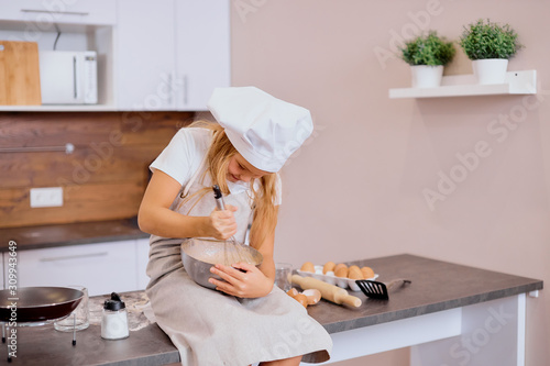 diligent and sedulous little girl cook and bake independently, make food at home without adults. portrait, isolated at home photo