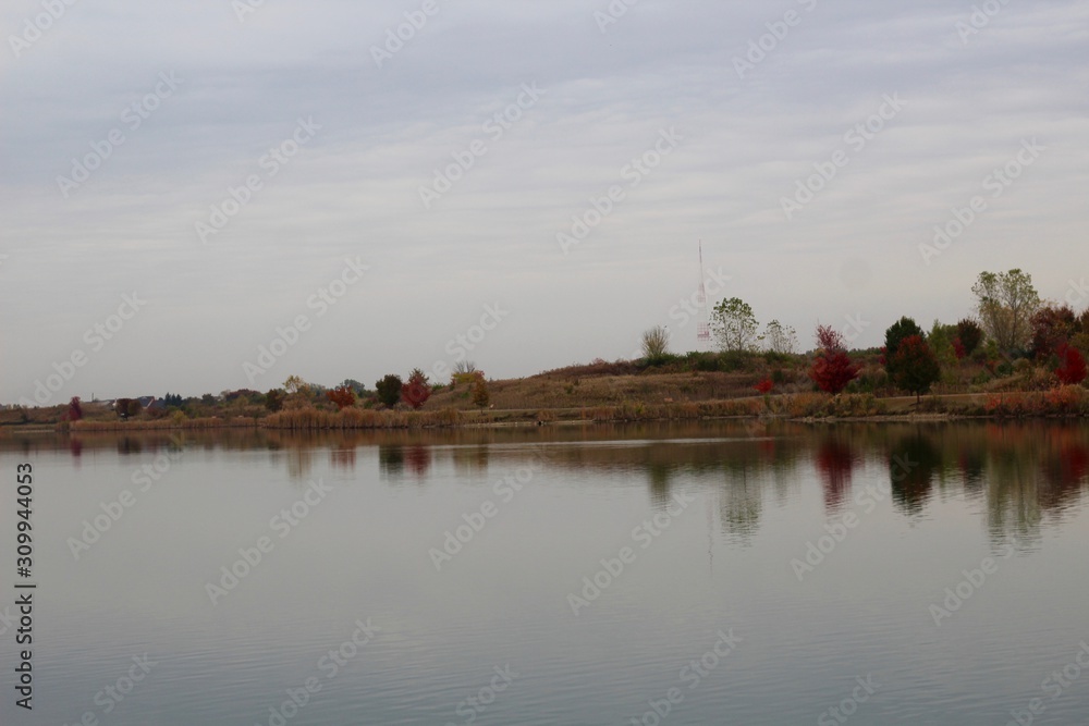 A calm colorful cloudy fall day at the lake in the park. A calm colorful cloudy fall day at the lake in the park.