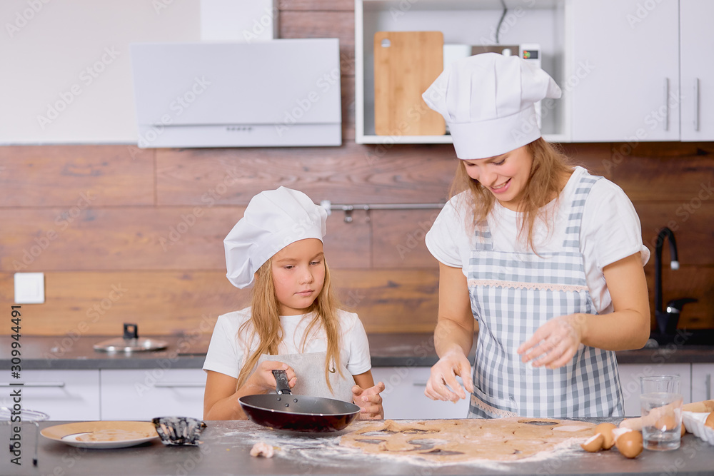 caucasian woman and child girl together in kitchen, woman teach kid girl to bake and cook, wearing aprons. generations and family concept caucasian woman and child girl together in kitchen, woman teach kid girl to bake and cook, wearing aprons. generations and family concept