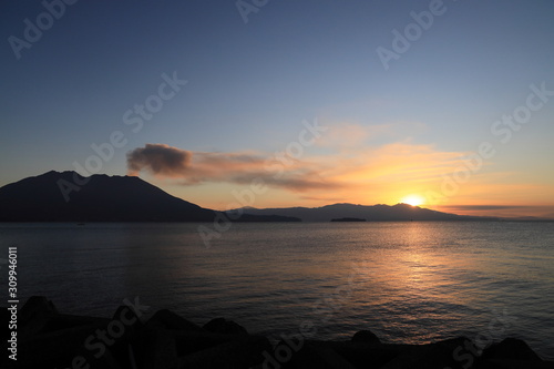 噴煙を上げる火山島と日の出