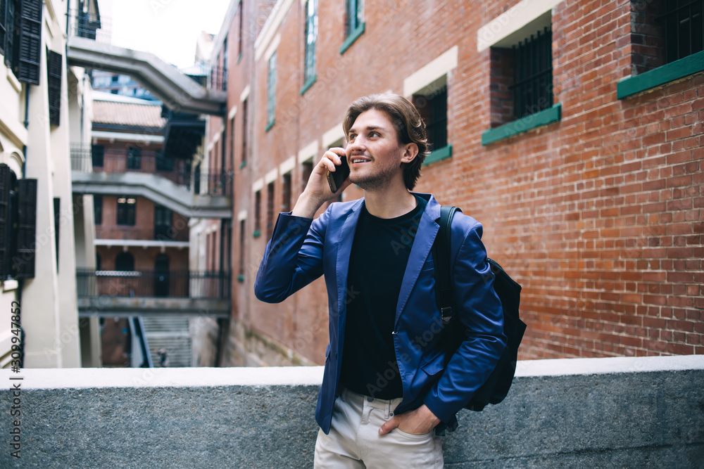 Fototapeta premium Cheerful male talking on smartphone on street