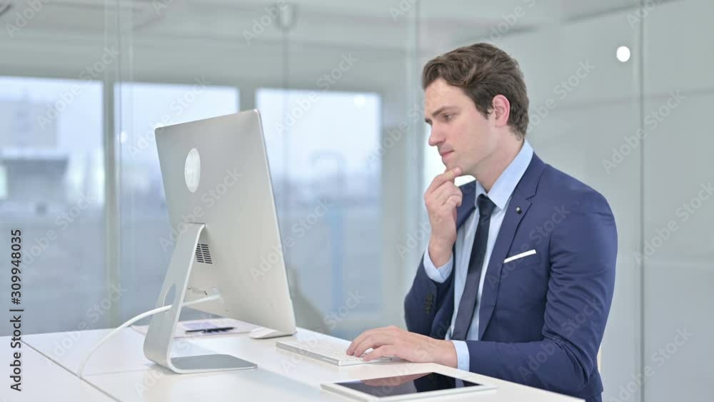 Young Businessman Thinking and Working on Desk Top in Office Young Businessman Thinking and Working on Desk Top in Office
