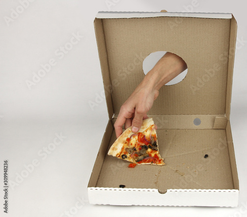 human hand through hole in cardboard  box takes last piece of pizza, white background, fastfood concept photo