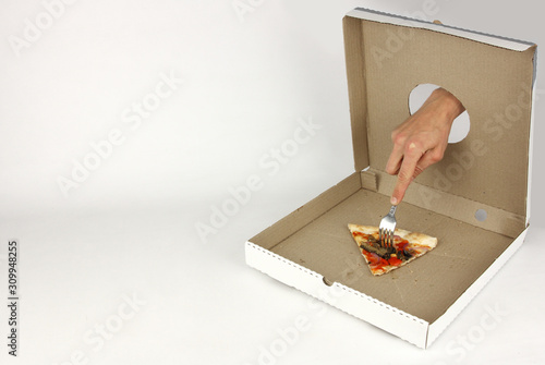 Fotografie hand through hole in fastfood cardboard box impales on fork the last slice of ve