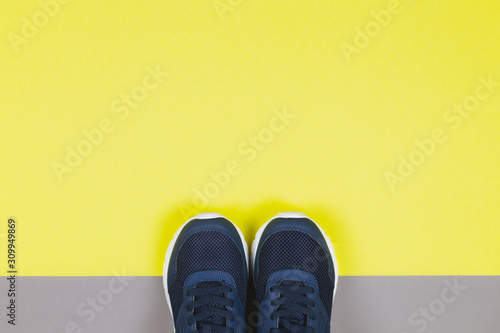 Classic blue sneakers on the yellow and grey background. Concept for healthy lifestyle and everyday training.