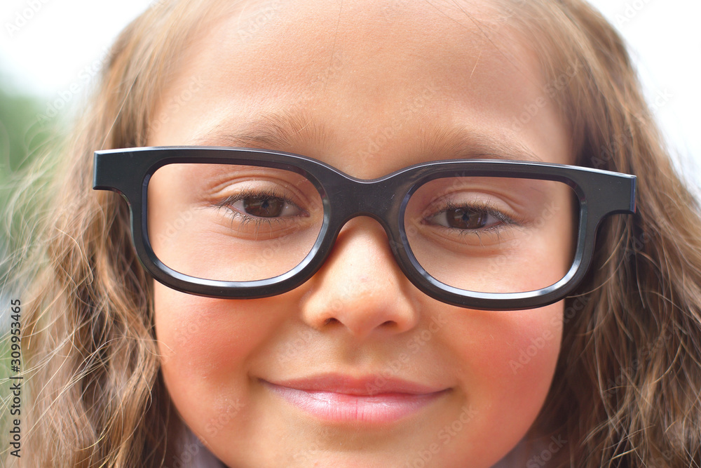 Portrait of beautiful young first-grader girl in eyeglasses. Focus on girls eyes Portrait of beautiful young first-grader girl in eyeglasses. Focus on girls eyes